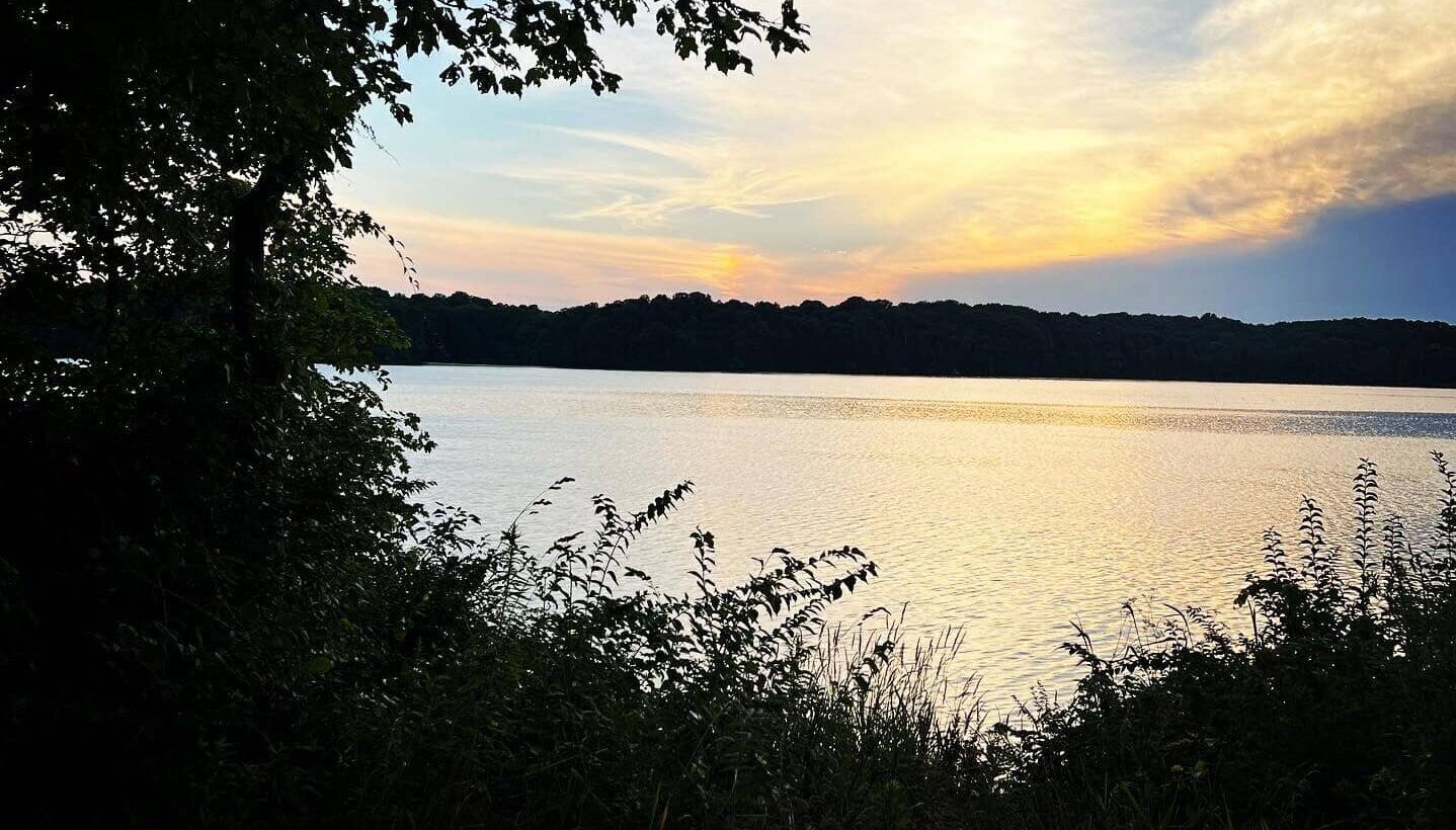 Photo from the shore overlooking at lake at sunset.