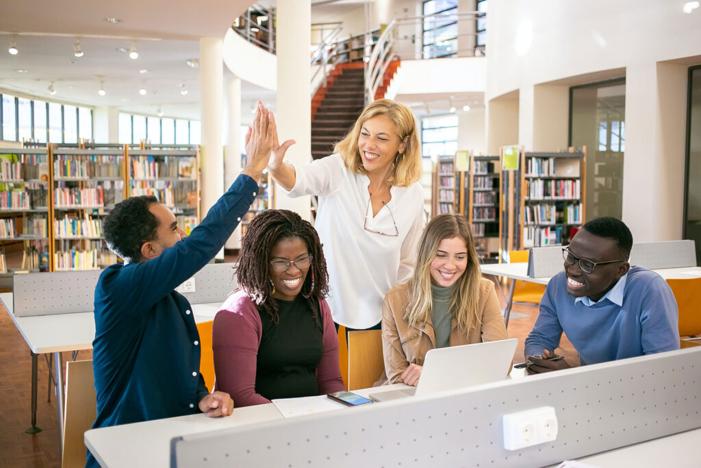 People smiling and high fiving in library.