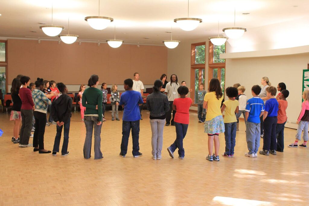 Adults speaking to a group of kids standing in a circle.