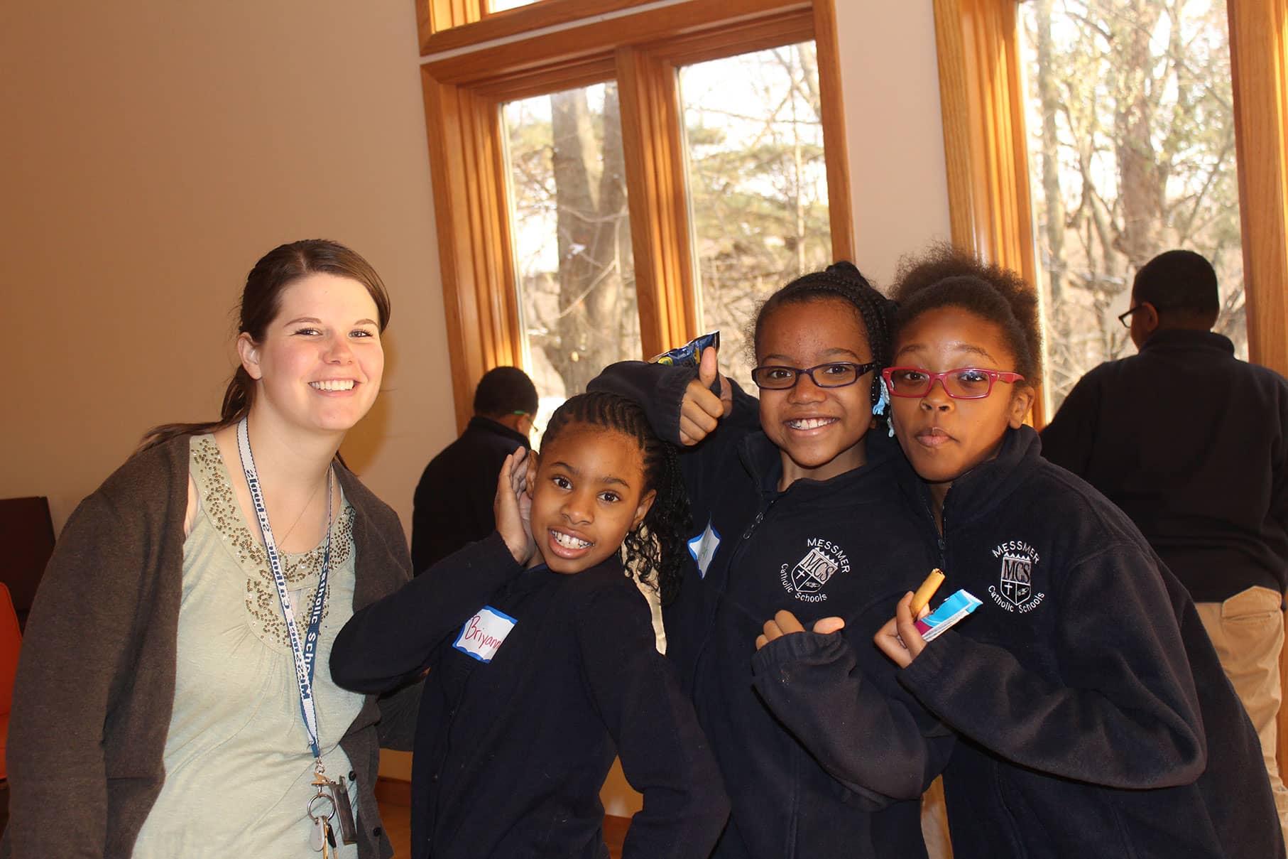A teacher with three students smiling at camera.