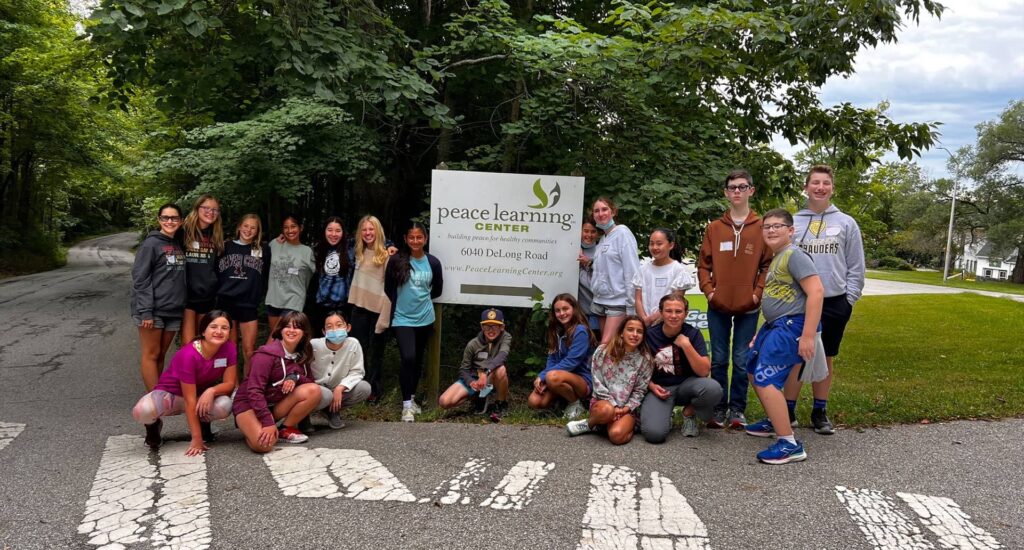 Group of kids standing around the Peace Learning Center sign.