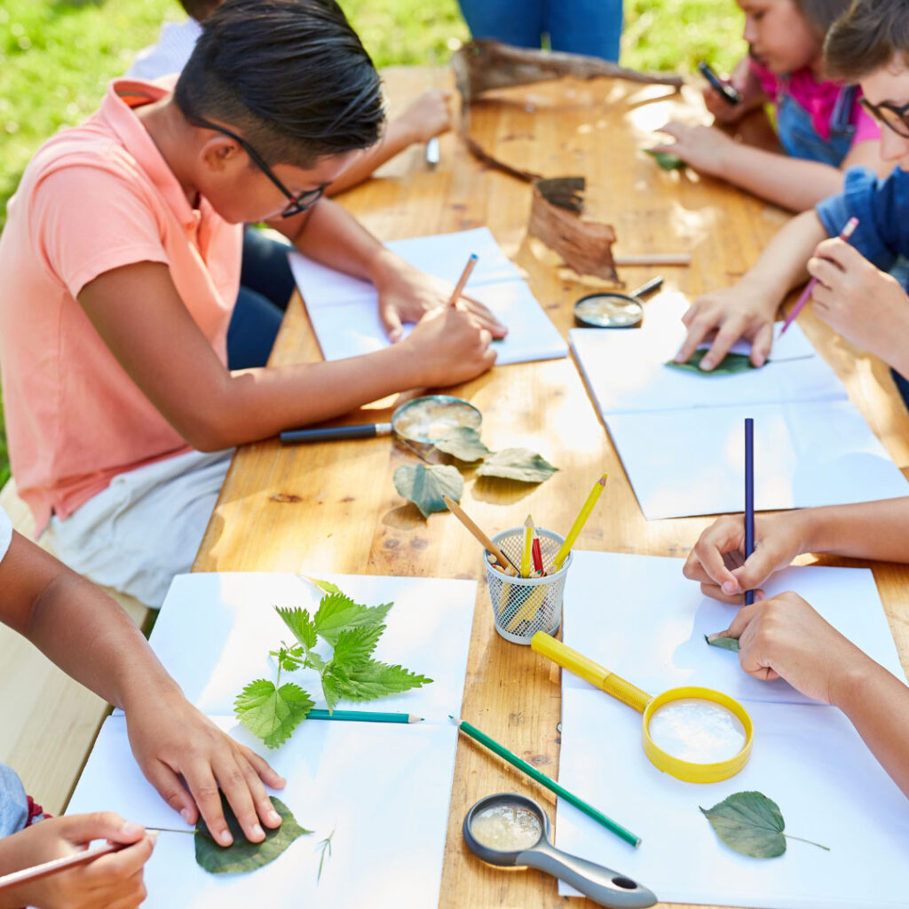 Kids tracing leaves at table outside