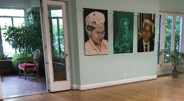 Room with paintings on wall and view of nature outside.